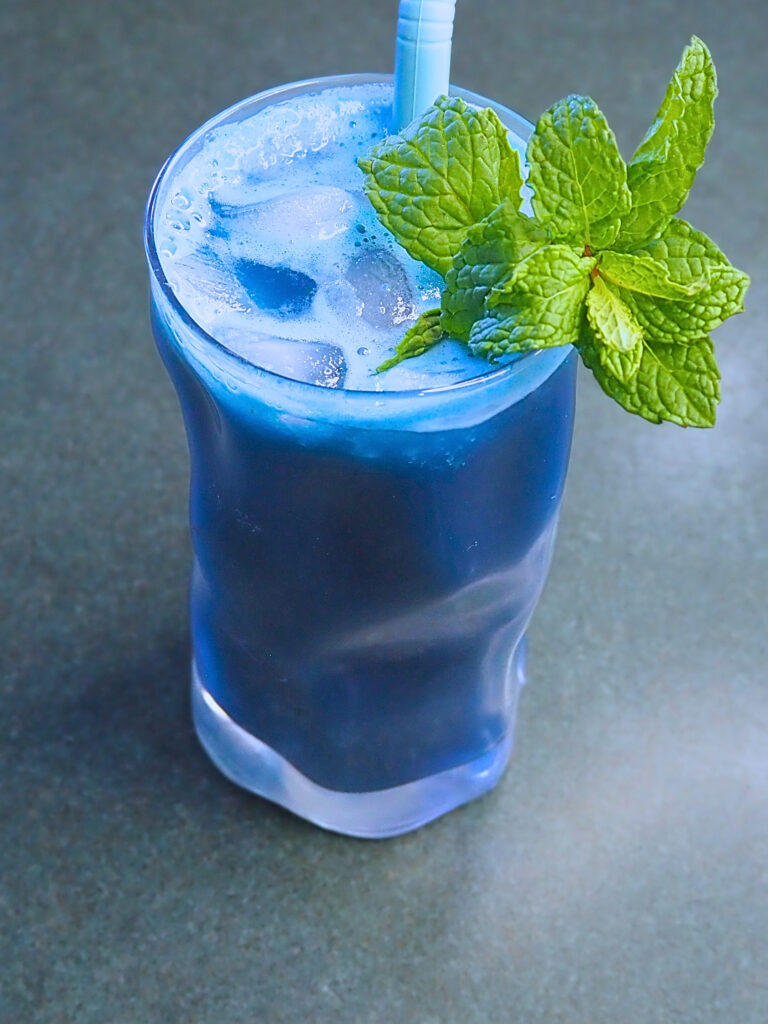 glass of blue spirulina juice with mint garnish