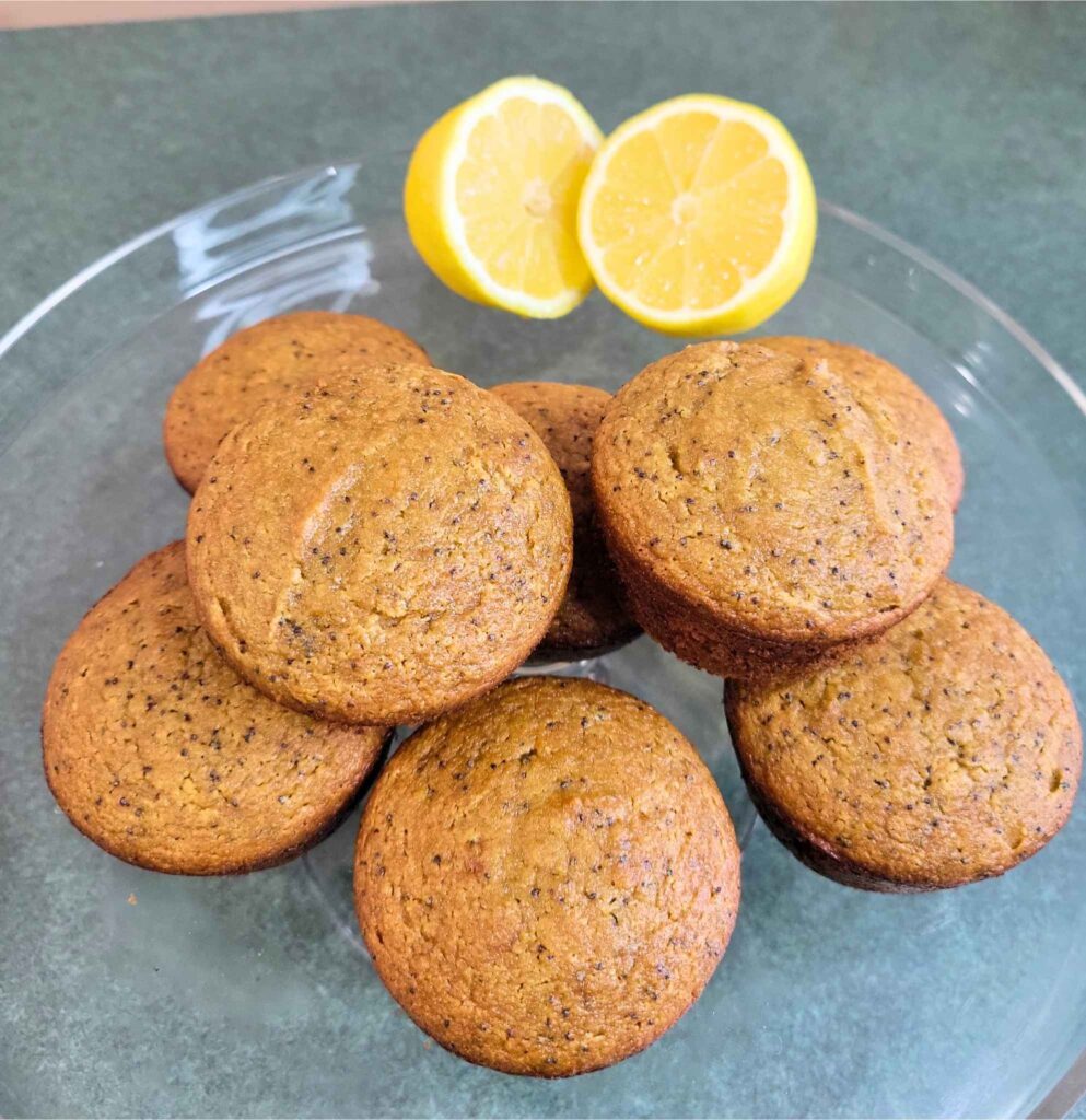 Gluten-free Lemon Poppy Seed muffins with fresh lemons on a cake platter