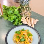 Finished serving of pineapple ginger chicken sauté on riced cauliflower and garnished with cilantro