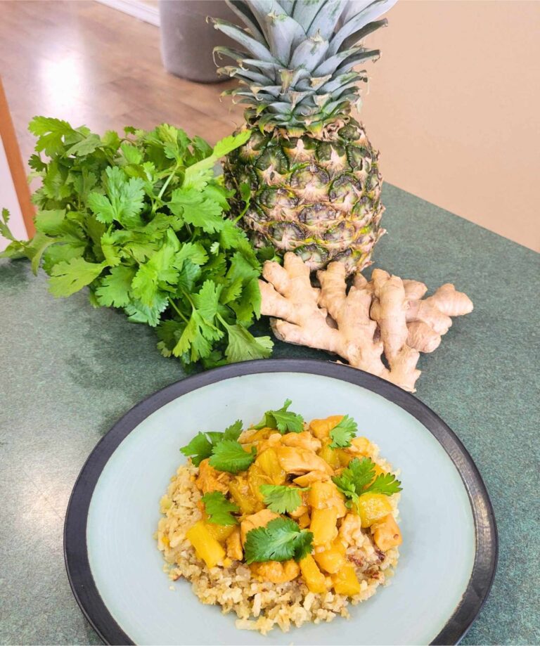 Finished serving of pineapple ginger chicken sauté on riced cauliflower and garnished with cilantro