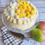 Gluten-free Mango Vanilla Cake with Dairy-free Coconut Cream frosting on a cake platter with fresh mangoes