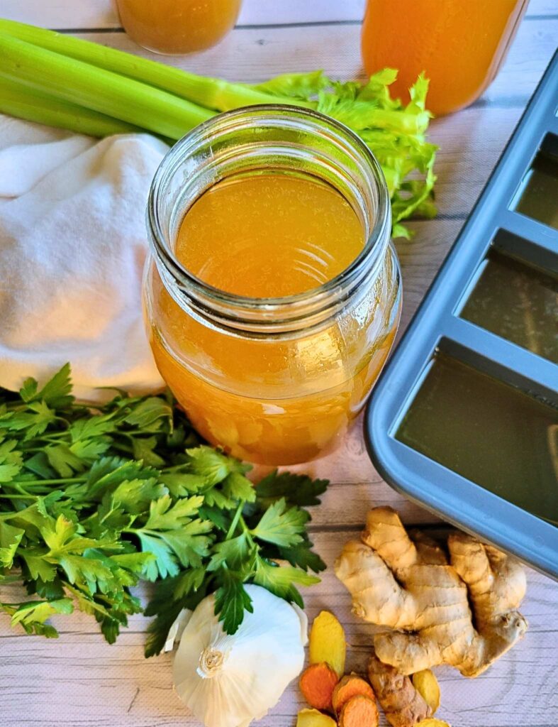 A jar of this gut-healing homemade bone broth surrounded by fresh anti-inflammatory ingredients