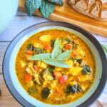 bowl of gut-healing pumpkin chicken soup with fresh sage garnish